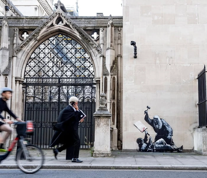 
    Banksy painted graffiti on the Royal Courts of Justice building in London, depicting a judge beating a protester with a hammer.