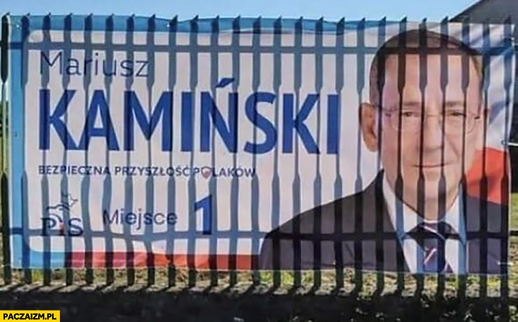 
    Mariusz Kamiński plakat wyborczy za kratami plot ogrodzenie